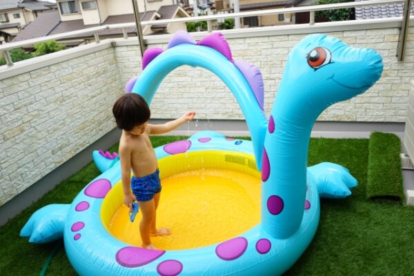 人口芝のベランダでプール遊びする子ども